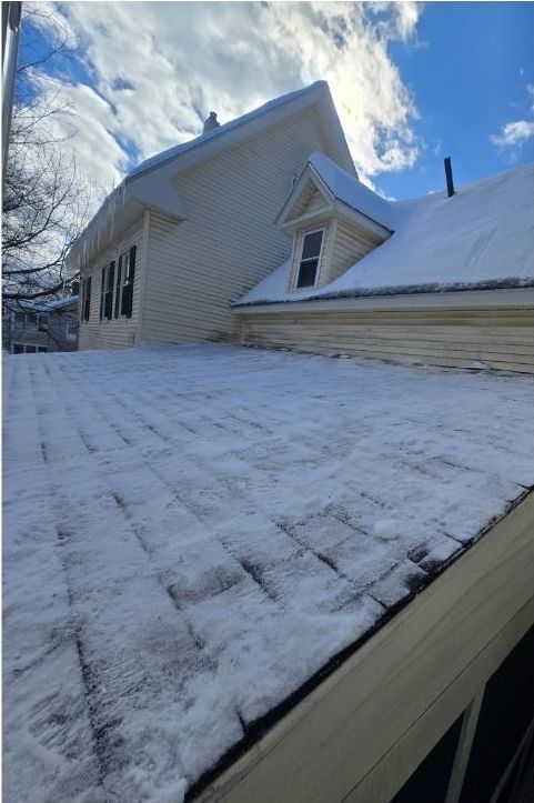 A snowy roof of a house with a blue sky in the background