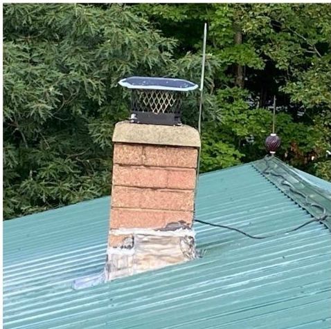 A brick chimney is sitting on top of a green roof.