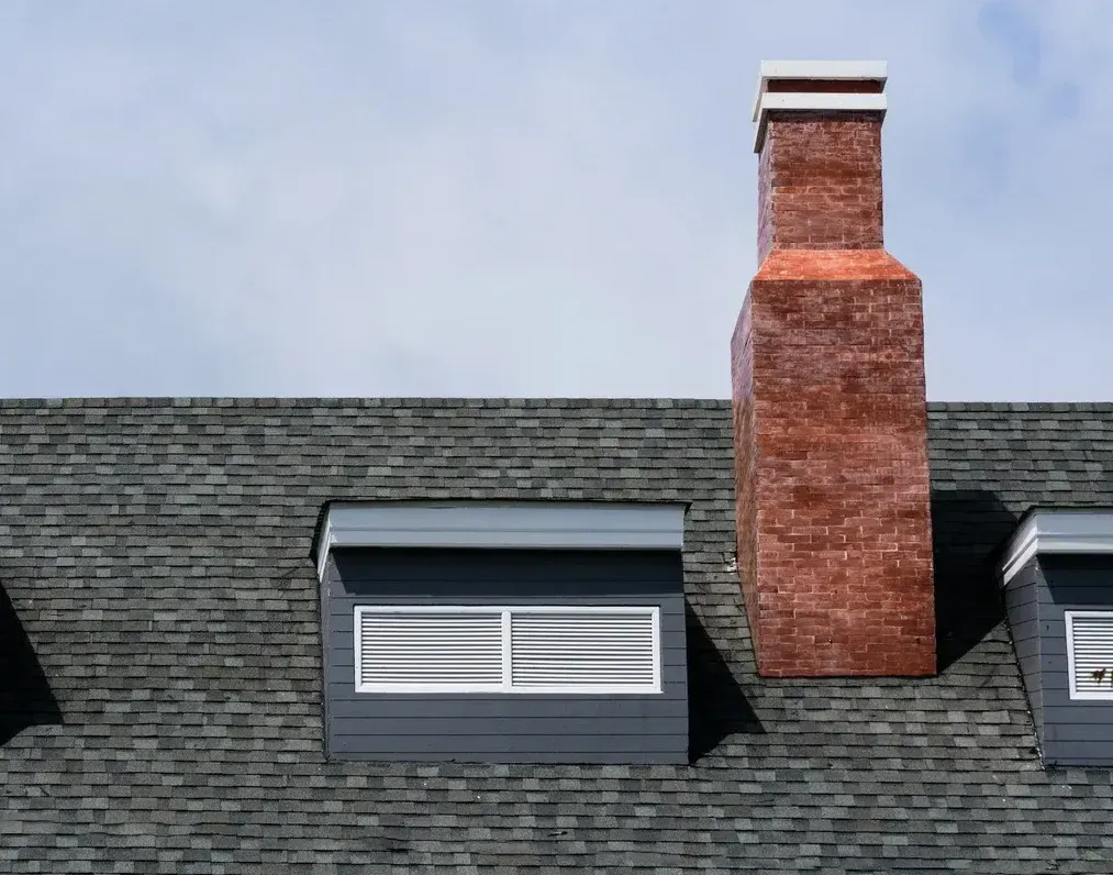 A brick chimney is on the roof of a house