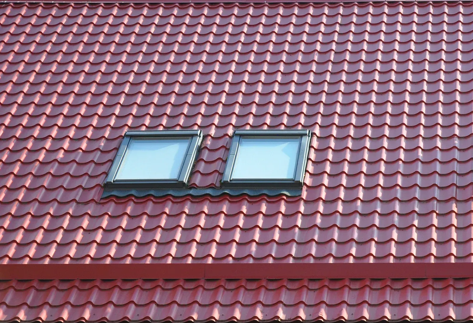 A red roof with two skylights on it