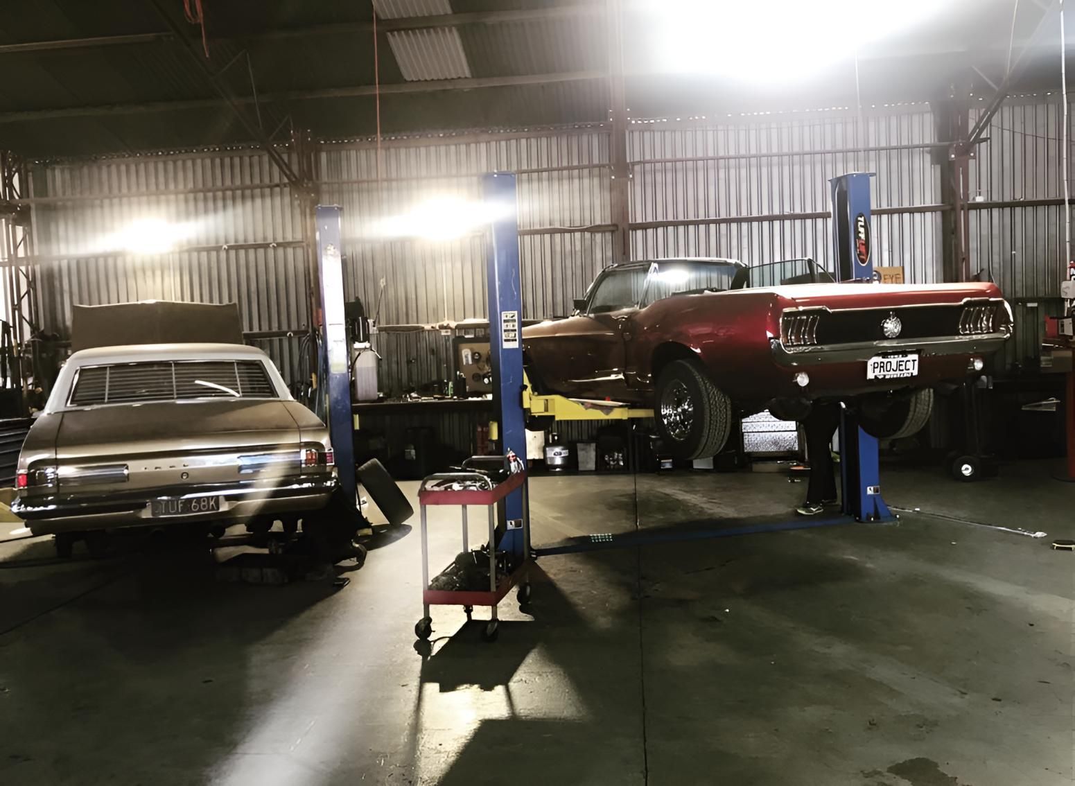 Two Cars Are Sitting On Lifts In A Garage — Territory Wrecking Repairs In Alice Springs, NT