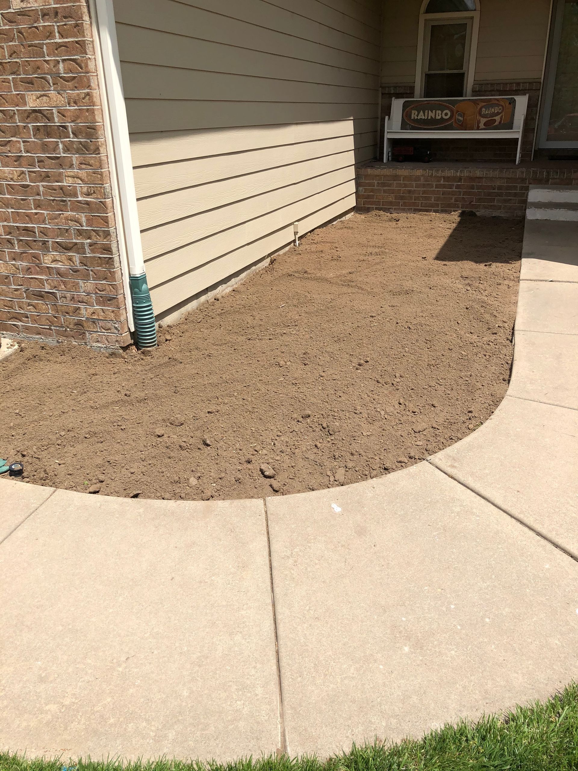 a concrete walkway leading to a house with a bench in the background .