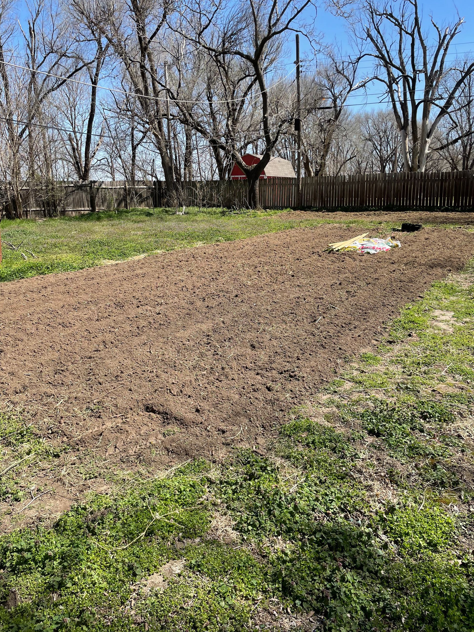 a dirt field with trees in the background and a fence in the background .