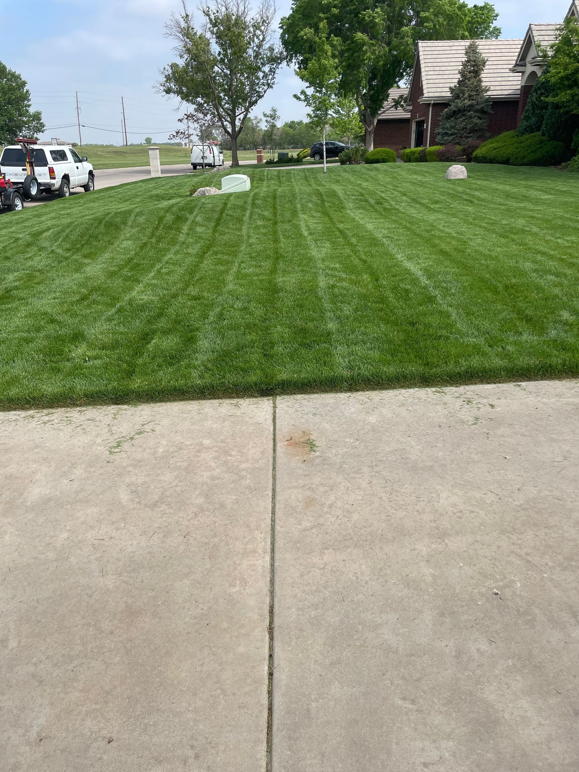 a lush green lawn with a concrete sidewalk in front of a house .
