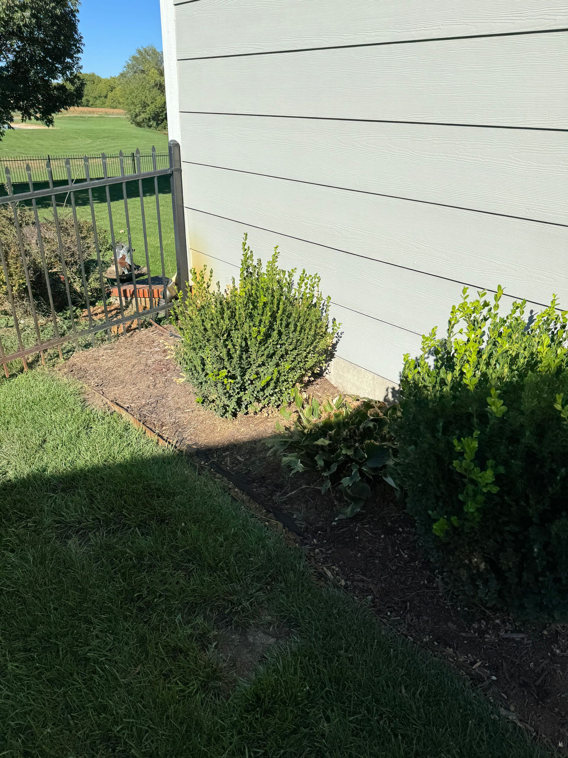 a white house with a fence and bushes in front of it