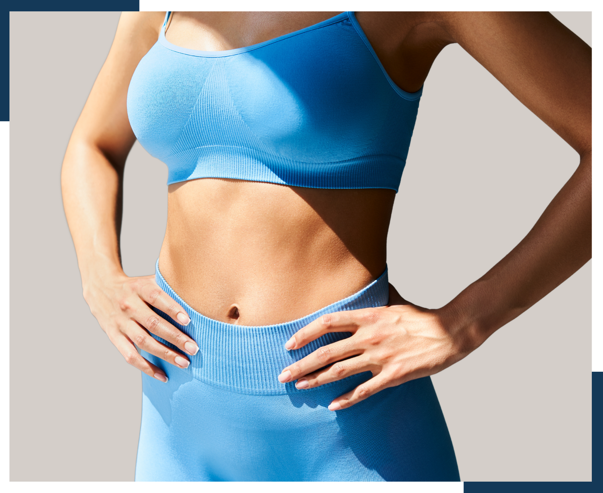 A woman in a blue sports bra and shorts is standing with her hands on her hips.