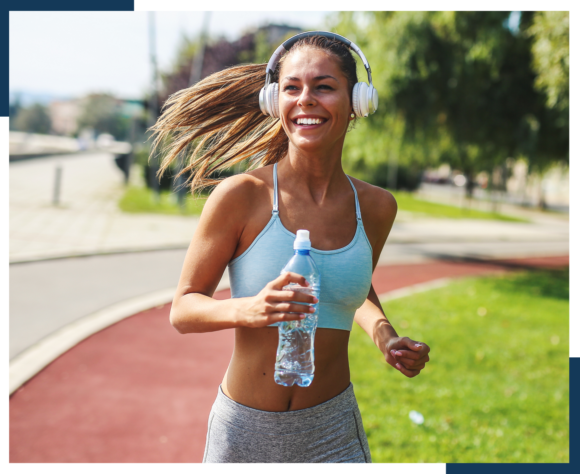 A woman wearing headphones is running with a bottle of water.