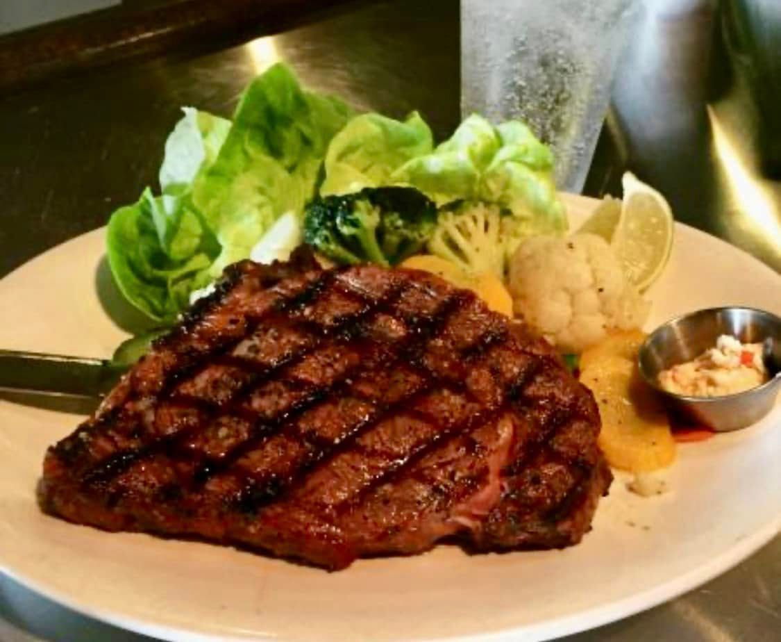 A white plate topped with a steak and vegetables