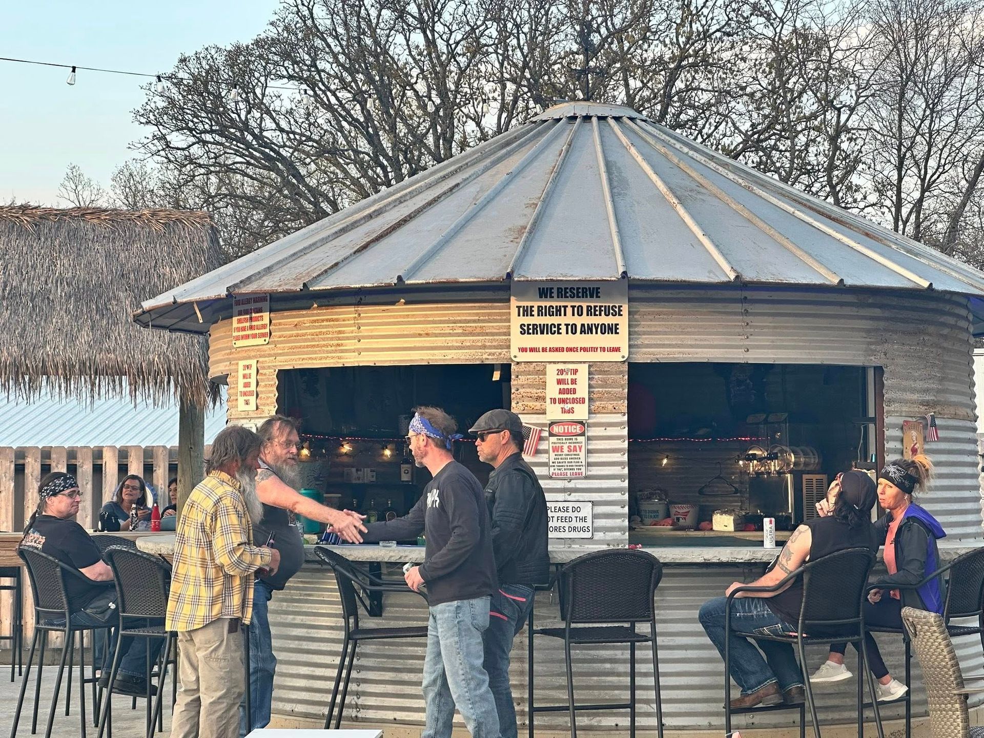 A group of people are sitting at tables in a restaurant outdoors