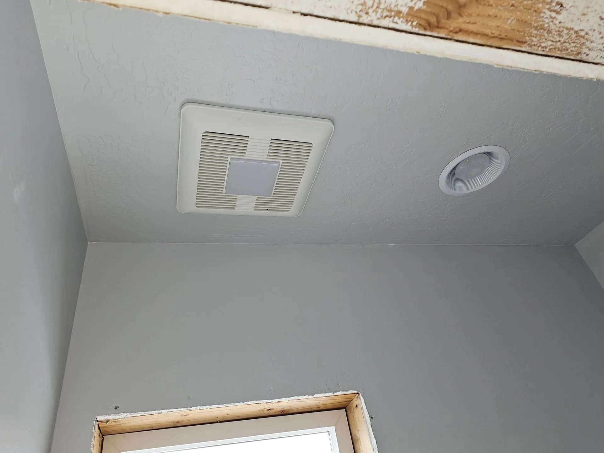 A bathroom with a fan and a light on the ceiling.