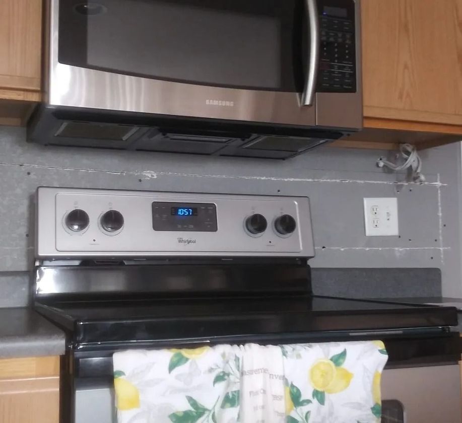 A stainless steel microwave is above a black stove