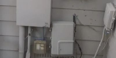A white box is attached to the side of a house.