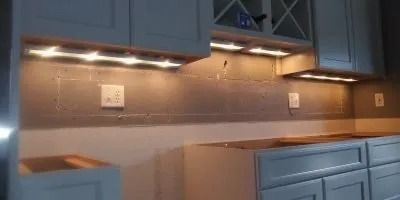 A kitchen with gray cabinets and a stove top oven.