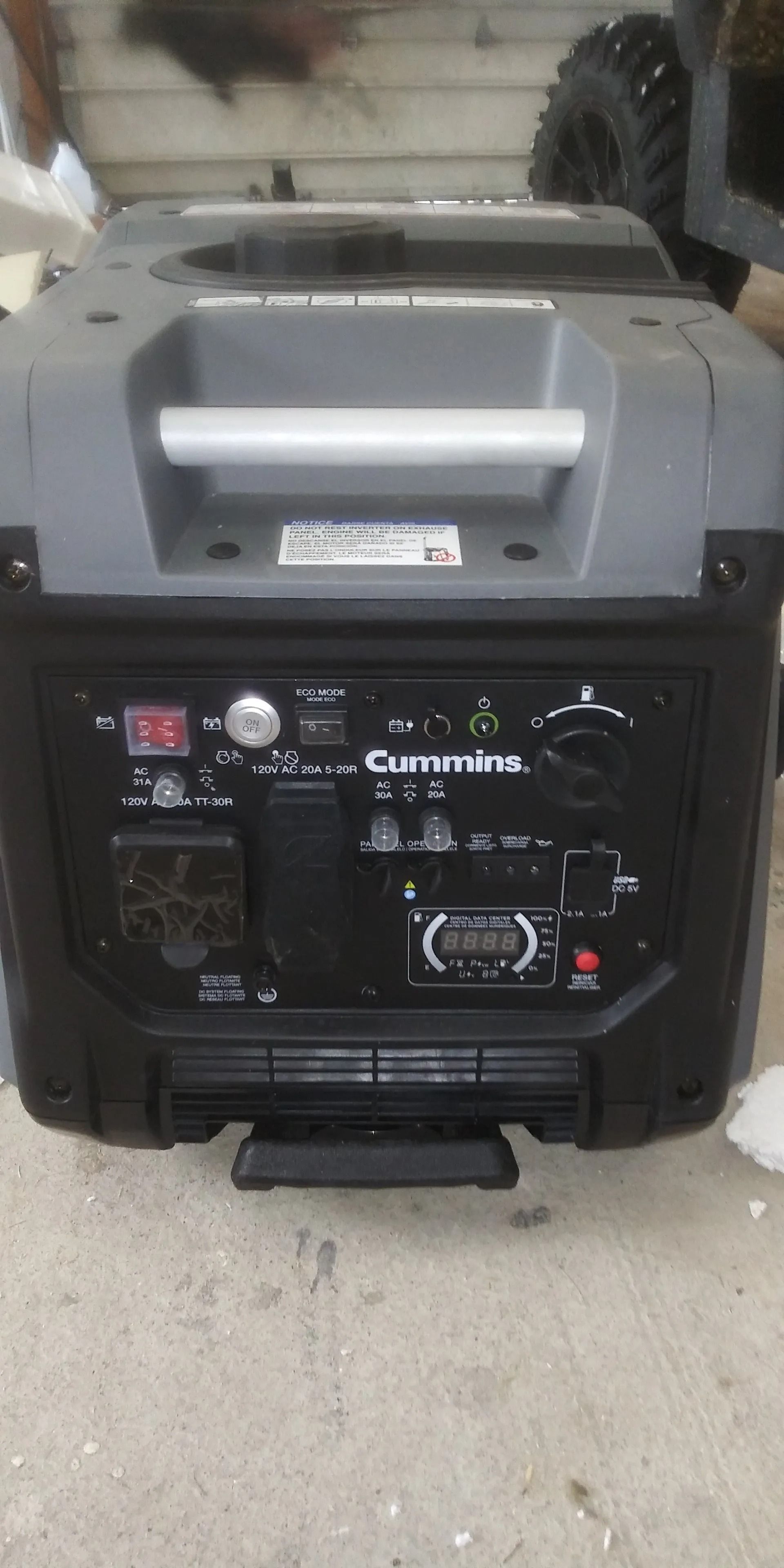 A black portable generator is sitting on top of a concrete floor.