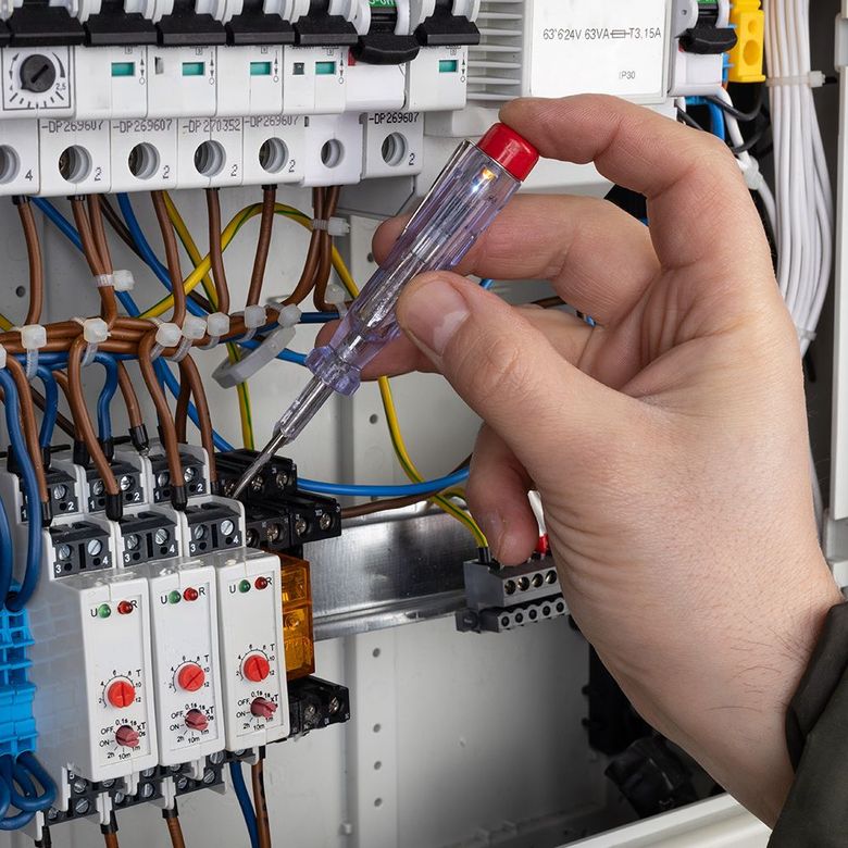 A person holding a screwdriver in front of an electrical box