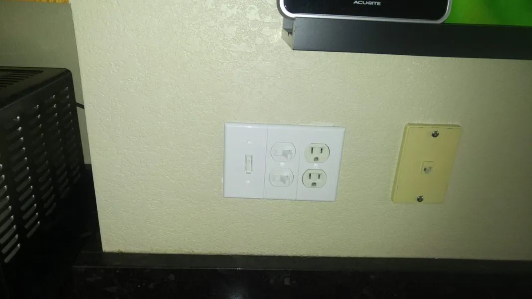 A white electrical outlet on a wall next to a tv