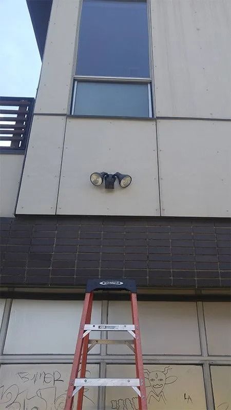 A ladder is sitting on the side of a building next to a window.