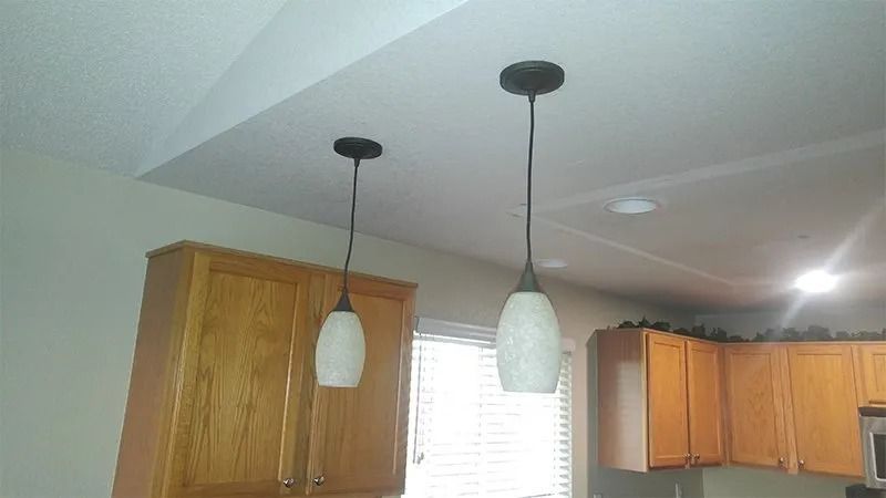 Two pendant lights are hanging from the ceiling of a kitchen.