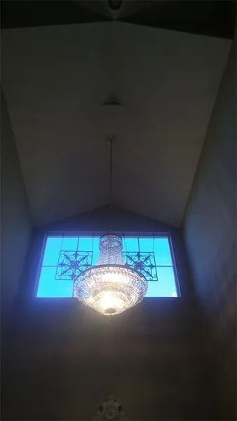 A chandelier is hanging from the ceiling in front of a stained glass window.