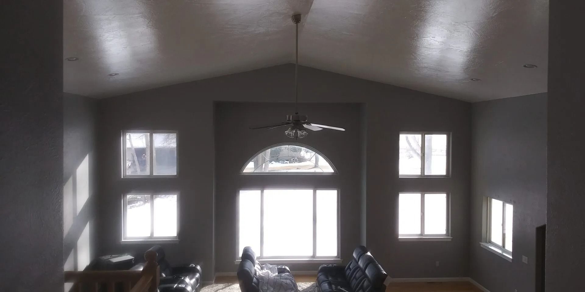A living room with a lot of windows and a ceiling fan.
