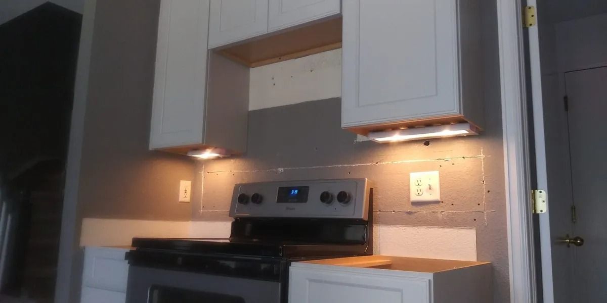 A kitchen with a stove , microwave , and cabinets.