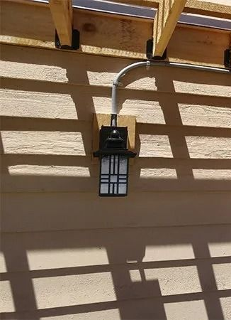 A wooden pergola is covering a patio with a sliding glass door.