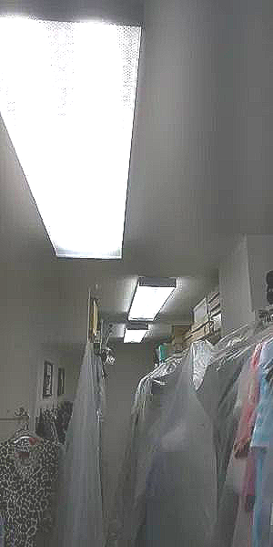 A closet filled with lots of clothes and a light on the ceiling.