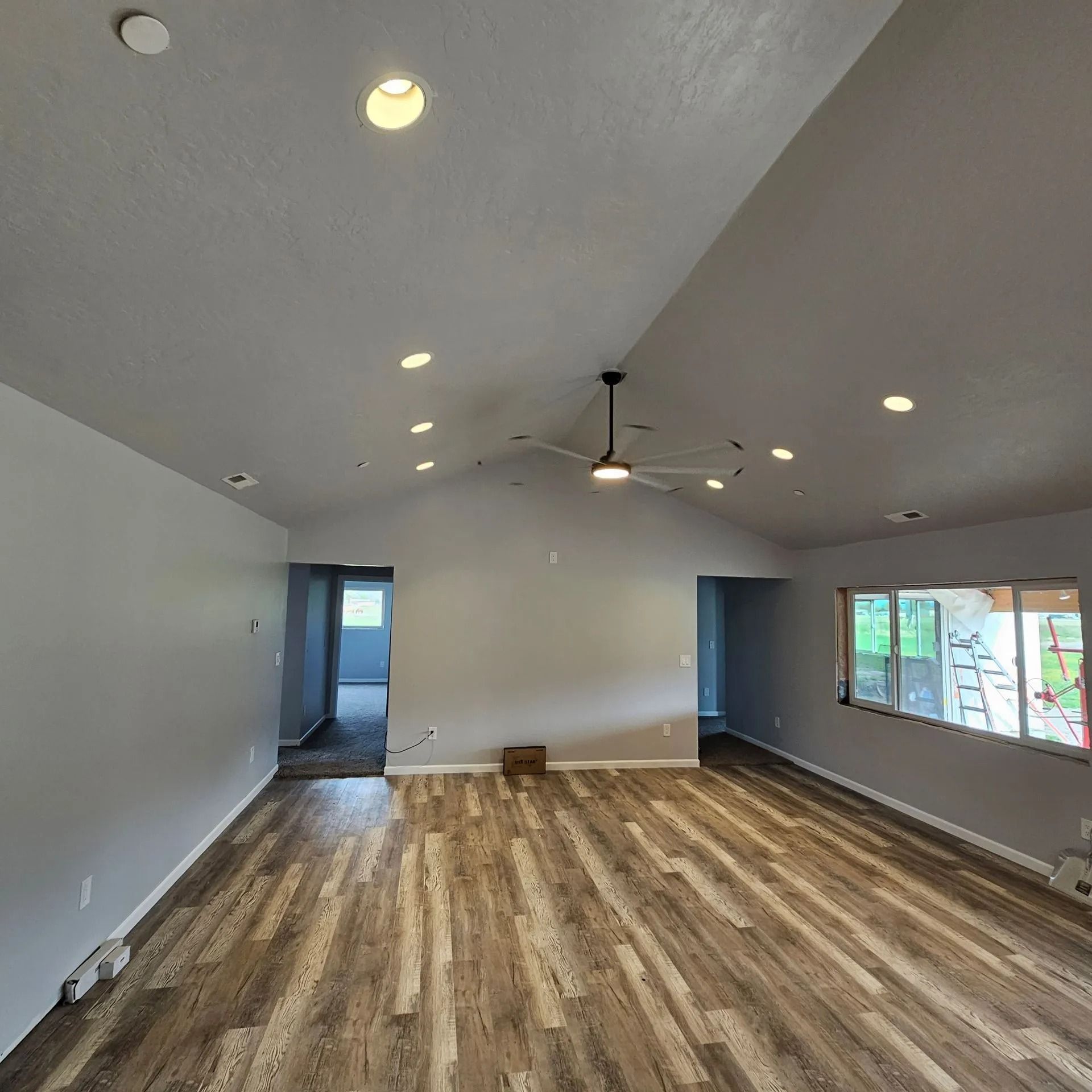 An empty living room with hardwood floors and a ceiling fan.