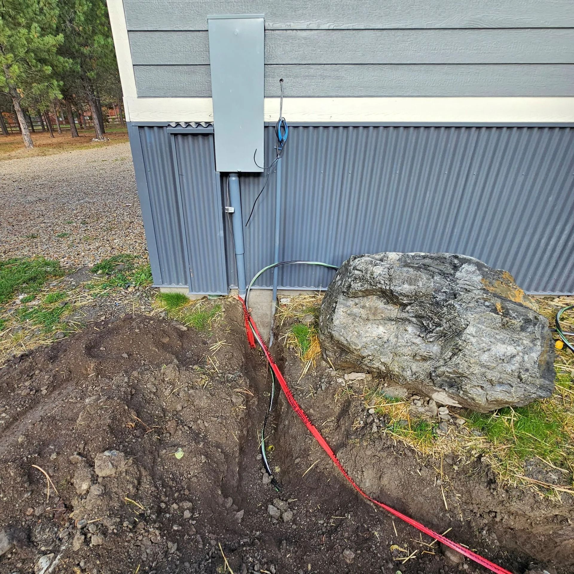 An electrical box is being installed on the side of a house.