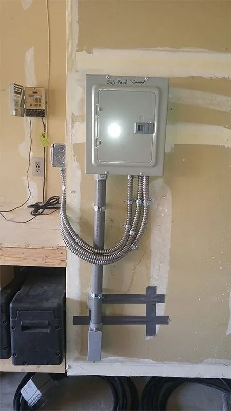 A electrical box is hanging on a wall in a room.