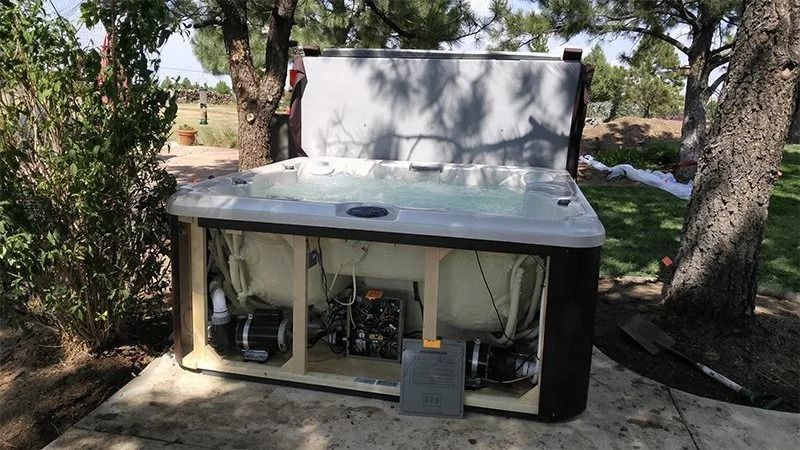 A hot tub is sitting under a tree in a yard.