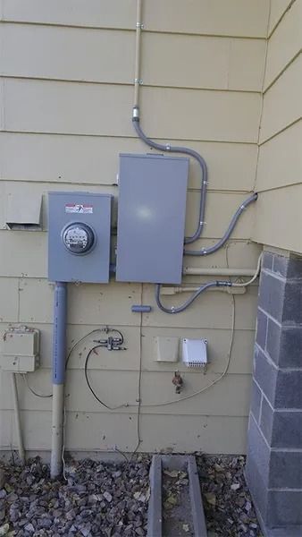 A electrical box is attached to the side of a house.