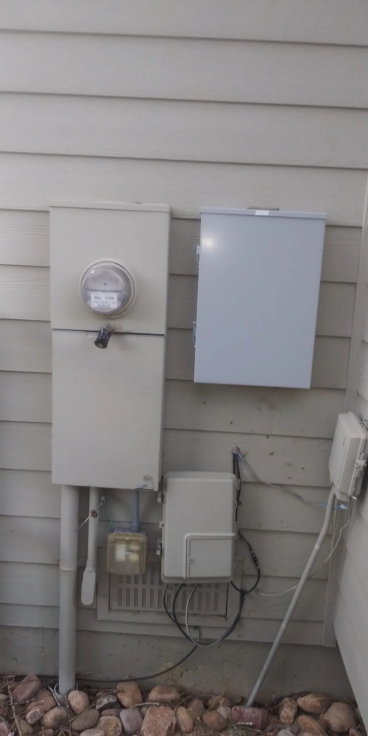 A white box is attached to the side of a house.