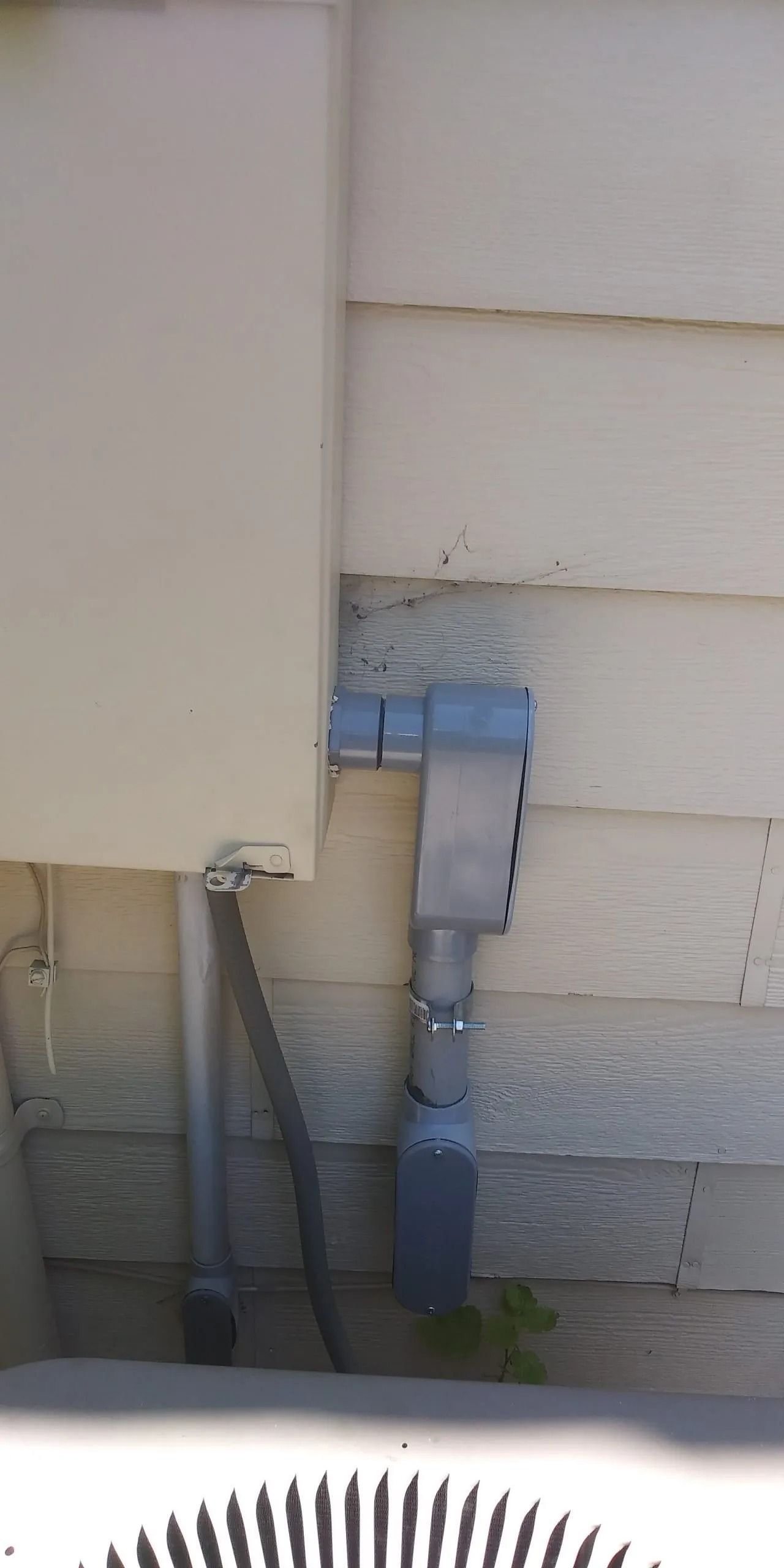 A white house with a blue pipe on the side of it.