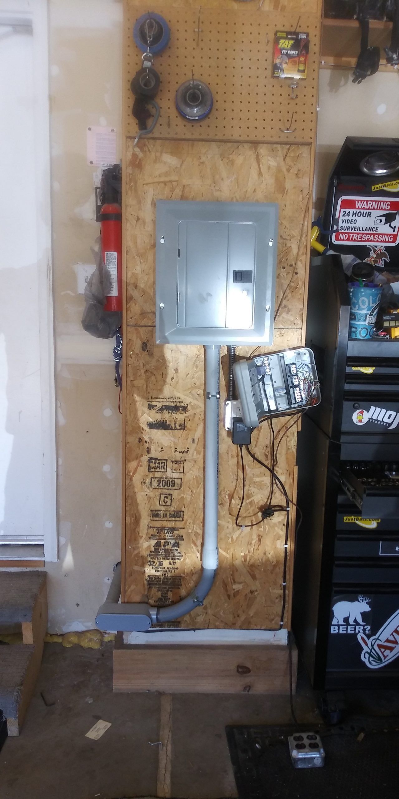 A electrical box is hanging on a wall in a garage.