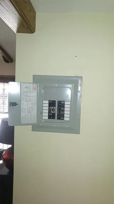 A electrical box is hanging on a wall in a room.