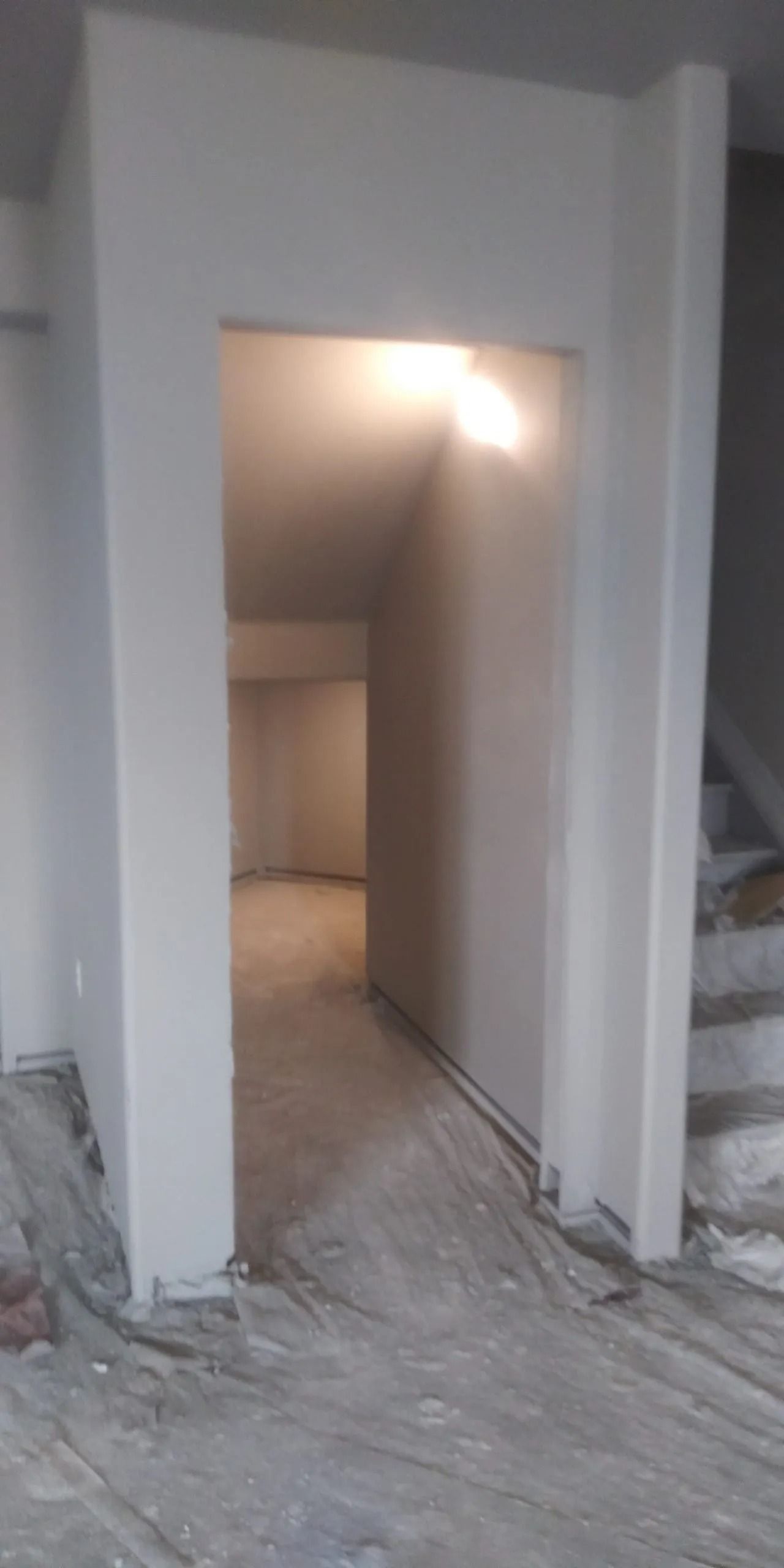 An empty room with a doorway leading to a staircase.