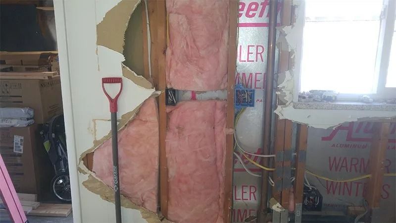 A room with a hole in the wall and a shovel in it.