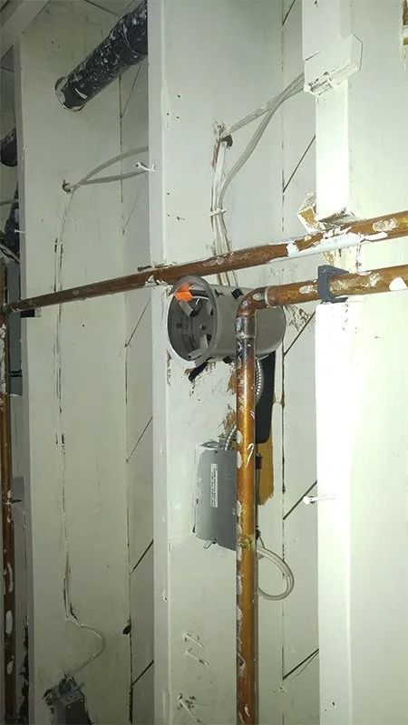 A room with a lot of pipes and wires on the wall.