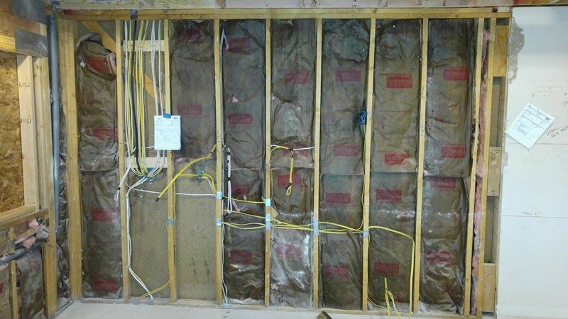A wall with a lot of insulation on it and a lot of wires coming out of it.