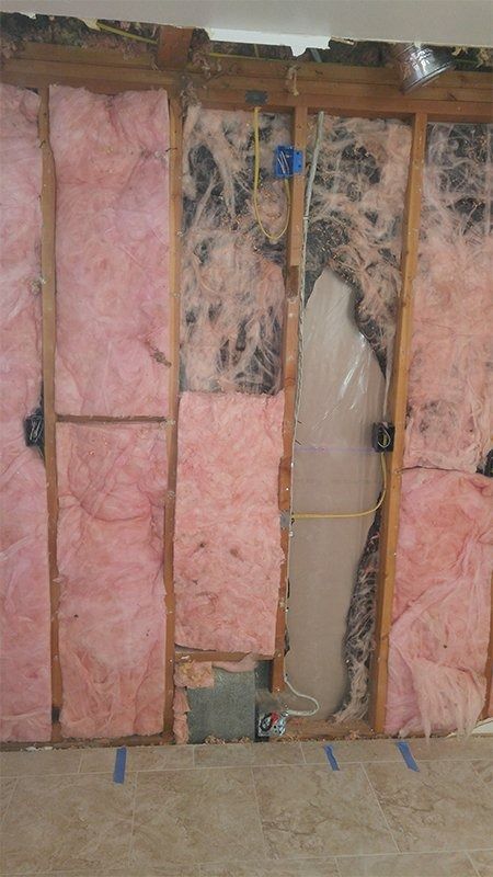 A room with pink insulation on the walls and a hole in the wall.
