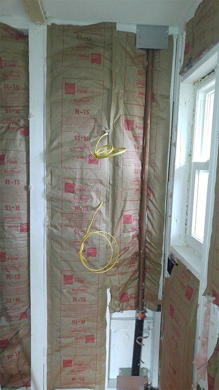 A room with a pipe hanging from the wall and a window.