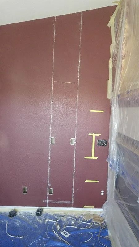 A room with a red wall and a blue tarp on the floor.