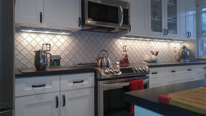A kitchen with white cabinets , stainless steel appliances , and a microwave.