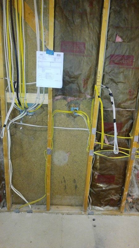 A wall with a lot of wires hanging from it and a sign on it.