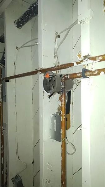 A room with a lot of pipes and wires on the wall.