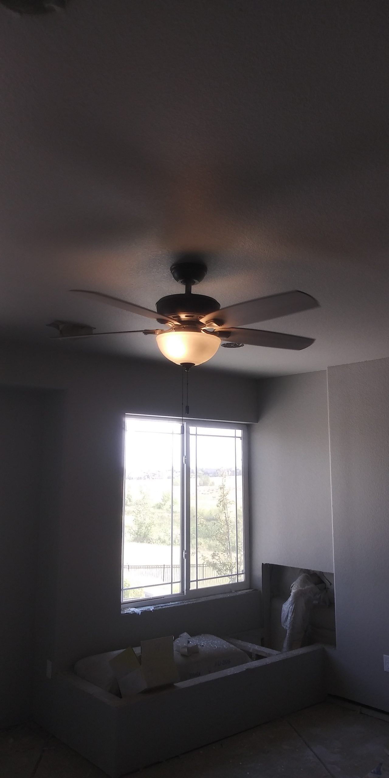 A bedroom with a ceiling fan and a window.