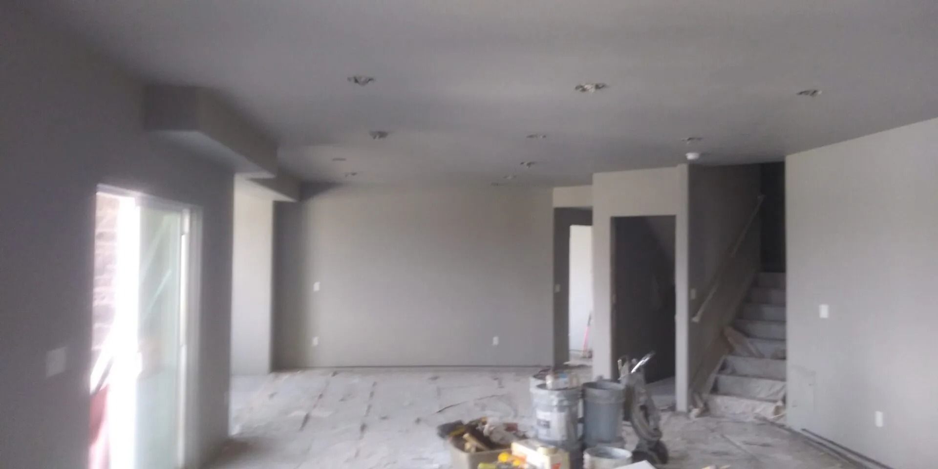 A large empty room with a staircase in the background.