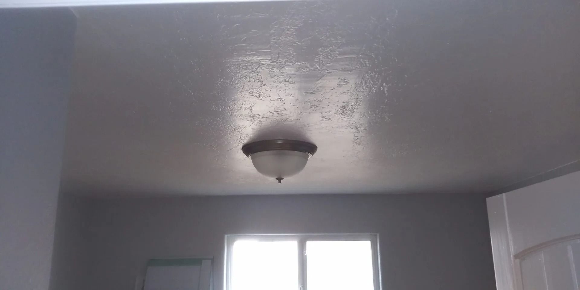 A ceiling light is hanging from the ceiling in a room with a window.