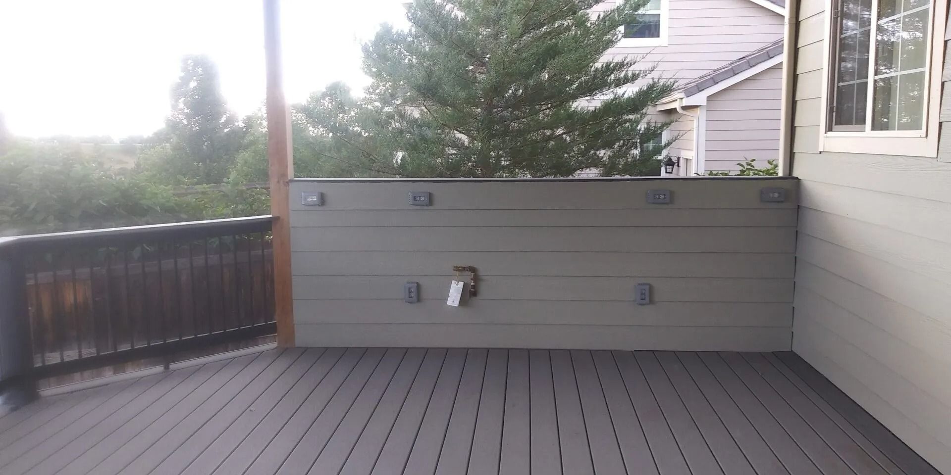 An empty deck with a fence and a window in front of a house.